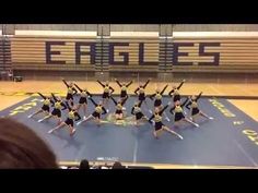 a group of cheerleaders standing on top of a blue mat in a gym