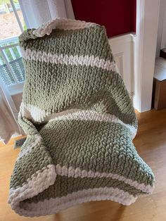 a green and white blanket sitting on top of a wooden floor next to a window