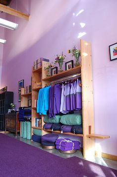 a room with purple carpet and wooden shelves filled with clothes on top of them,