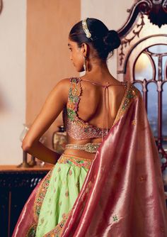 Embrace timeless elegance with this classic kalidar lehenga set, crafted from light green jacquard silk banarasi. Featuring intricate embroidery enhanced with zari and zardozi work, the design is further adorned with dabka, sequins, pearls, and gota texturing. The ensemble includes a heavily embroidered blouse made from pastel pink silk zari tissue, adorned with a floral embroidery pattern and embellished with pearl tassels. Complementing the set is a shimmering pastel pink silk zari tissue dupatta, featuring floral embroidered motifs and a patchwork embroidered border. A signature embellished belt creates a gracefully defined and sophisticated silhouette. Tissue Dupatta, Pearl Tassels, Zardozi Work, Embroidered Motifs, Embellished Belt, Floral Embroidery Patterns, Embroidered Border, Intricate Embroidery, Silk Organza