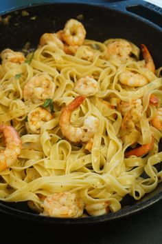 a pan filled with pasta and shrimp on top of a stove