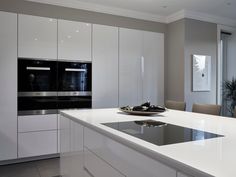 a modern kitchen with white cabinets and an island in the middle is seen from across the room