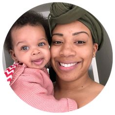 a woman holding a baby in her arms and wearing a green head scarf on top of her head