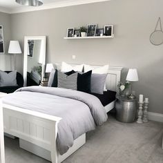 a white bed sitting in a bedroom next to two black and white lamps on either side of the bed