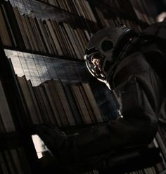 a man in a helmet is standing next to a book shelf