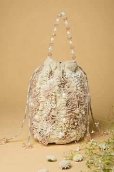 Cream and ivory potli bag with all over hand embroidery using Japanese beads and baguettes work. - Aza Fashions Cream Evening Bucket Bag In Pouch Shape, Cream Evening Bucket Bag Pouch, Evening Cream Bucket Bag, Cream Bucket Bag With Pearl Handle, Beige Embellished Rectangular Bag, Beige Embroidered Evening Shoulder Bag, Elegant Cream Pouch Bucket Bag, Beige Embroidered Shoulder Bag For Evening, Beige Bucket Shoulder Bag With Pearl Handle