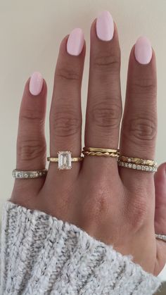 a woman's hand with three different rings on her fingers and one is wearing a sweater