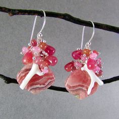 I love these focals! They are Argentine rhodochrosite gems and measure 22x20mm. They have been wrapped in sterling silver wire and dangle below a gorgeous combination of smooth ruby briolettes, pink moonstone, pink sapphire, white branch coral. Each bead is meticulously wrapped onto it's own head pin. The entire cluster is topped. I have used simple sterling ear wires. The earrings measure 1 3/4 (44mm.) from the top of the ear wires. Unique Pink Gemstone Earrings, Unique Pink Jewelry With Gemstone Accents, Sterling Silver Pink Wire Wrapped Earrings, Pink Sterling Silver Wire Wrapped Earrings, Pink Gemstones For Gifts, Unique Pink Gemstones For Gifts, Unique Pink Sterling Silver Earrings, Pink Natural Stones Gemstones In Sterling Silver, Pink Sterling Silver Earrings With Gemstone Accents