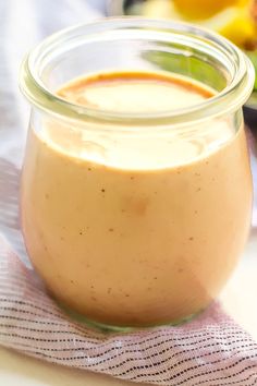 a glass jar filled with liquid sitting on top of a table next to a plate of food