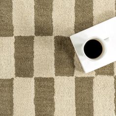 a cup of coffee sitting on top of a white and brown checkered floor mat