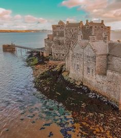 an old castle sitting on top of a cliff next to the ocean