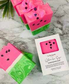 two pink and green watermelon soaps sitting on top of a marble counter