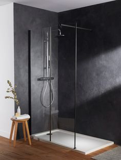 a bathroom with a walk in shower next to a wooden floor and black painted walls