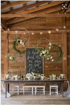 a table with wreaths and flowers on it in front of a chalkboard sign