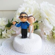 a wedding cake topper with a bride and groom figurine next to white flowers