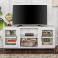 a flat screen tv sitting on top of a white entertainment center next to a lamp