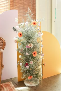 an arrangement of flowers in a vase next to a chair