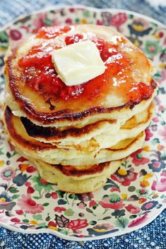 a stack of pancakes with butter and syrup on top, sitting on a floral plate