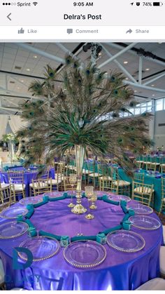 peacock feathers decorate the centerpieces on this purple tableclothed round dining room