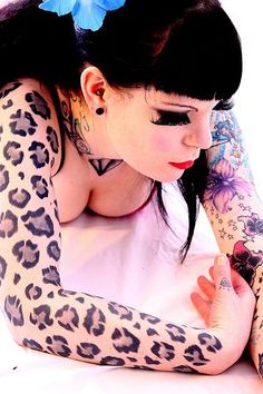 a woman with tattoos on her arms and arm is leaning down to the ground while wearing a white dress