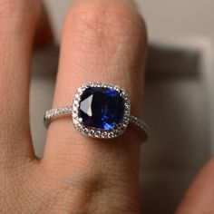 a close up of a person's hand holding a ring with a blue stone