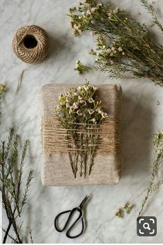 a bunch of flowers sitting on top of a table next to twine spools