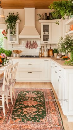 a kitchen filled with lots of white furniture and flowers on top of a rug in front of an oven