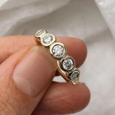 a hand holding a gold ring with three diamonds