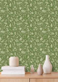 a green wallpaper with white flowers and leaves on it, next to two vases