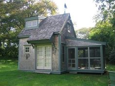 a small gray and white house in the grass