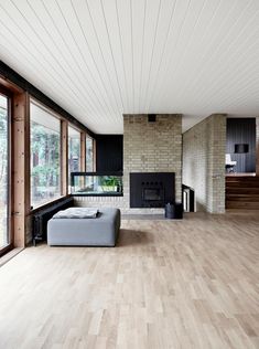 an empty living room with wood floors and white walls, along with large windows that look out onto the outdoors