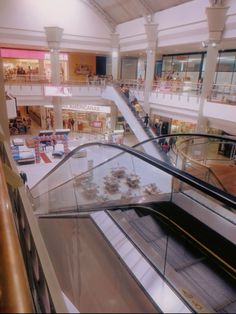 an escalator in a shopping mall with people walking down it and on the other side