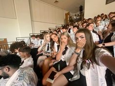 a group of people sitting next to each other in front of a crowd with their hands on their mouths