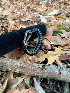 a rope wrapped around a piece of wood on the ground covered in leaves and fallen branches