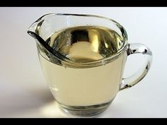 a glass pitcher filled with liquid sitting on top of a white countertop next to a spoon