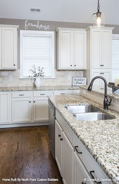 a kitchen with white cabinets and marble counter tops