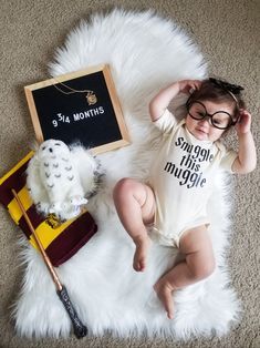 a baby wearing glasses laying on the floor next to a harry potter sign