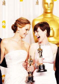 two women in white dresses holding their oscars