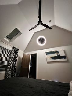 a ceiling fan is mounted to the ceiling in a bedroom with white walls and black bedding