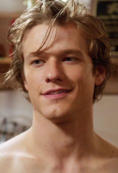 a shirtless young man in a kitchen looking at the camera