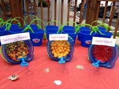 several buckets filled with fruit sitting on top of a red tablecloth covered table