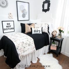 a bedroom with black and white bedding, pictures on the wall and rugs