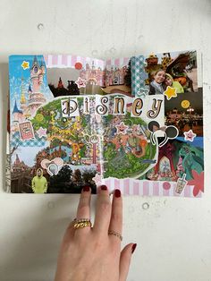 a person's hand is holding an open book with images of disney on it