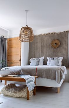 a bedroom with white floors and wooden walls, decorated in natural materials such as blankets and pillows