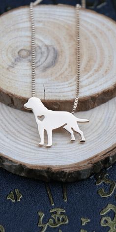 a necklace with a dog on it sitting on top of a piece of wood