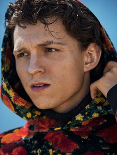 a young man with curly hair wearing a hoodie and looking off into the distance