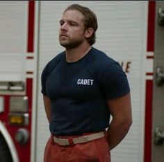 a man standing in front of a fire truck wearing a cadet t - shirt