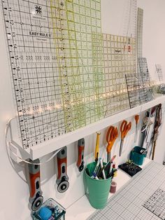 scissors are hanging on the wall with rulers and other crafting tools in buckets