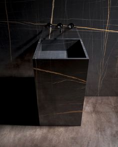 a black sink sitting on top of a wooden counter next to a wall mounted faucet