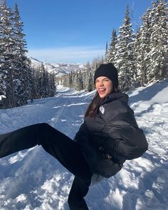 a woman is sitting in the snow with her legs spread out and smiling at the camera